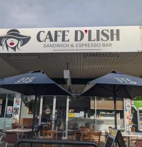 Front entrance of Cafe D’lish in Deakin with outdoor seating and umbrellas under the Sandwich & Espresso Bar signage