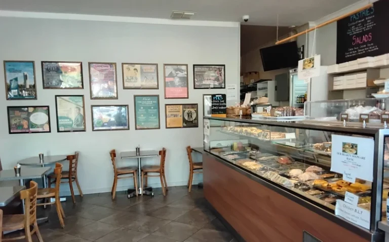 Inside Cafe D’lish with seating area and display cabinet filled with fresh pastries and sandwiches