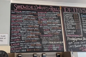 Chalkboard menu at Cafe D’lish displaying a wide selection of sandwiches, wraps, rolls and drinks